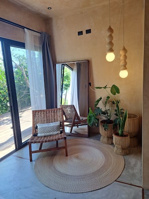 Relax in a serene space with a wicker chair, round rug, and lush greenery.