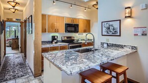 A modern kitchen with wooden cabinets, a granite countertop, a built-in microwave, and a stainless steel sink. - Stunning Third Story Condo with Stunning Mountain Views (Keystone)