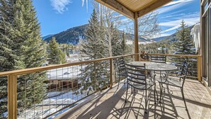 A balcony with a table and chairs, overlooking a snowy mountain landscape. - Stunning Third Story Condo with Stunning Mountain Views (Keystone)