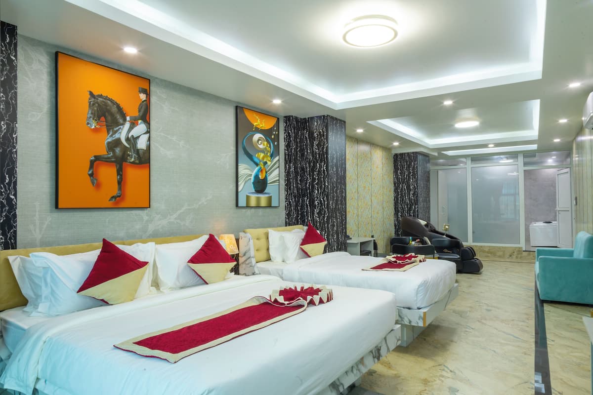 A hotel room with two beds, a massage chair, and a massage table.