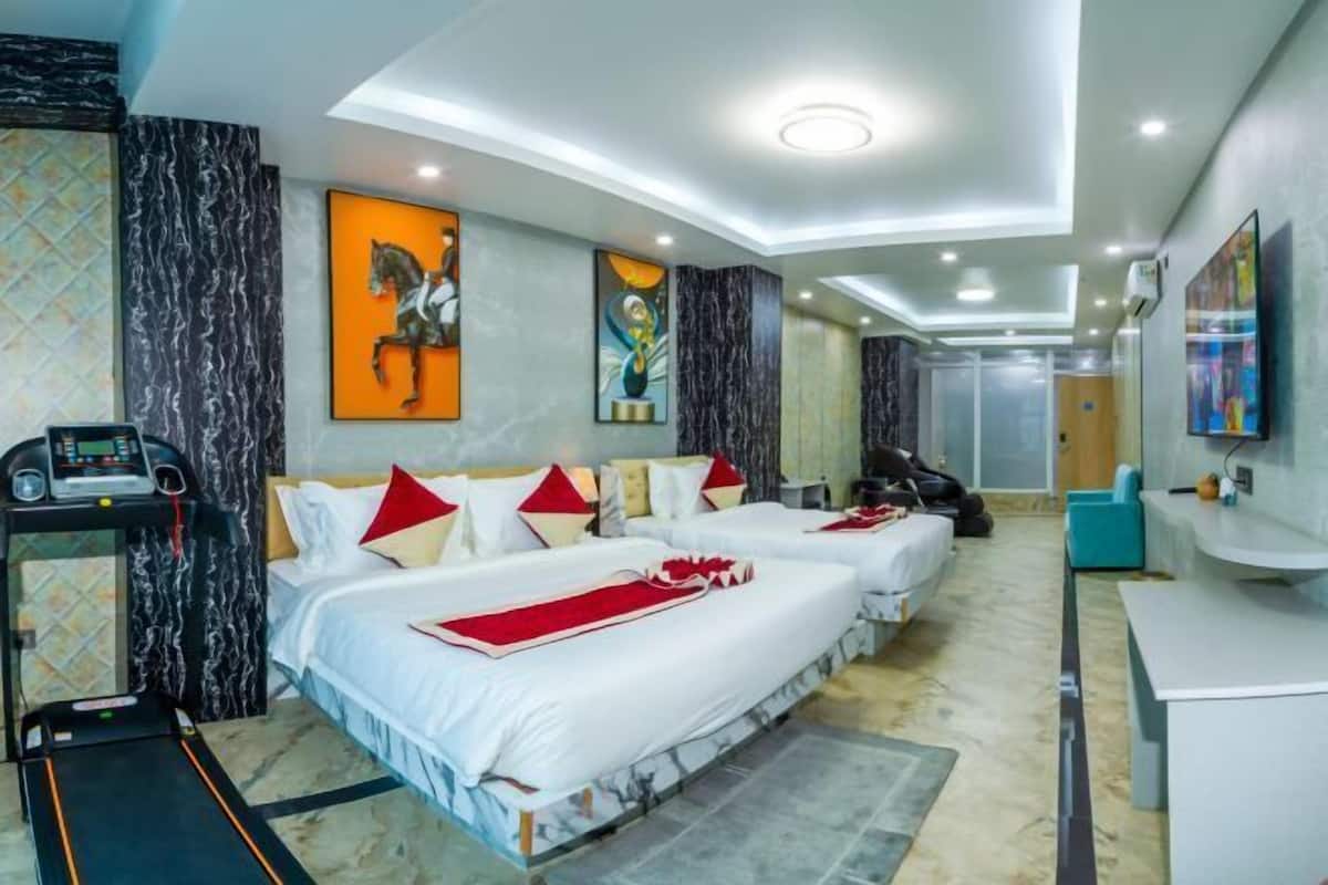 A hotel room with two beds, a treadmill, a desk, and artwork on the walls.