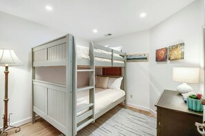 Ein Schlafraum mit Stockbetten, Schreibtisch, Lampe und Wandbildern.
