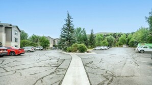 A parking lot with multiple cars, a central walkway, and surrounding greenery. - Located in Edwards close proximity to shops and restaurants! (Edwards)