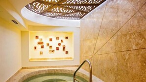 Un espace spa comprenant un bain à remous, un sol carrelé et un mur orné de tableaux.