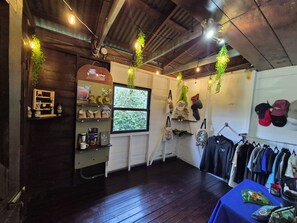 A cozy room with wooden floors, a coffee shop area, and a clothing rack. - Glampling Nubes de Monteverde (Monteverde)