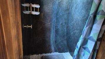 A compact bathroom with a toilet, a shower area, and a small shelf.
