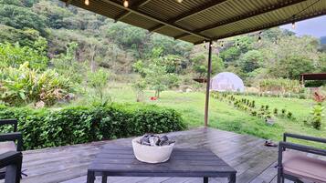 Relax under the stars in a shaded patio area with a fire pit, surrounded by lush greenery and a tranquil atmosphere.
