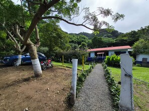 A gravel path leading to a building with a red roof, surrounded by greenery and trees. - Glampling Nubes de Monteverde (Monteverde)