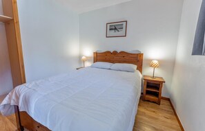 A bedroom with a wooden bed, white bedding, two bedside tables with lamps, and a framed picture on the wall.