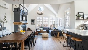 A modern kitchen with a wooden dining table, bar stools, and a built-in island. - Tremblant Prestige - Les Eaux 233-3 (Mont-Tremblant)