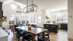 A spacious kitchen with a central island, bar stools, and a dining table with chairs. - Tremblant Prestige - Les Eaux 233-3 (Mont-Tremblant)