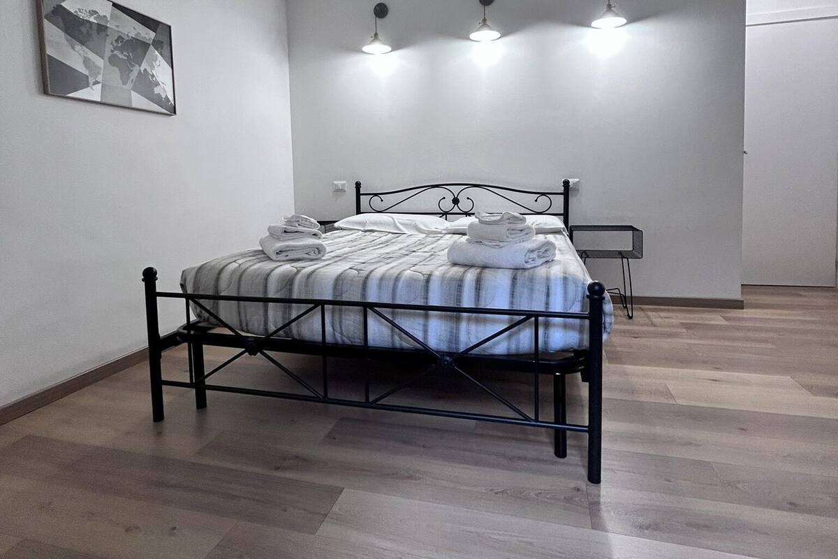 A bedroom with a bed, a wall-mounted light fixture, and a framed picture.