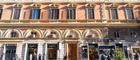 Un immeuble à plusieurs étages dont le rez-de-chaussée abrite des boutiques, notamment « Unicredit » et « Oysho ».
