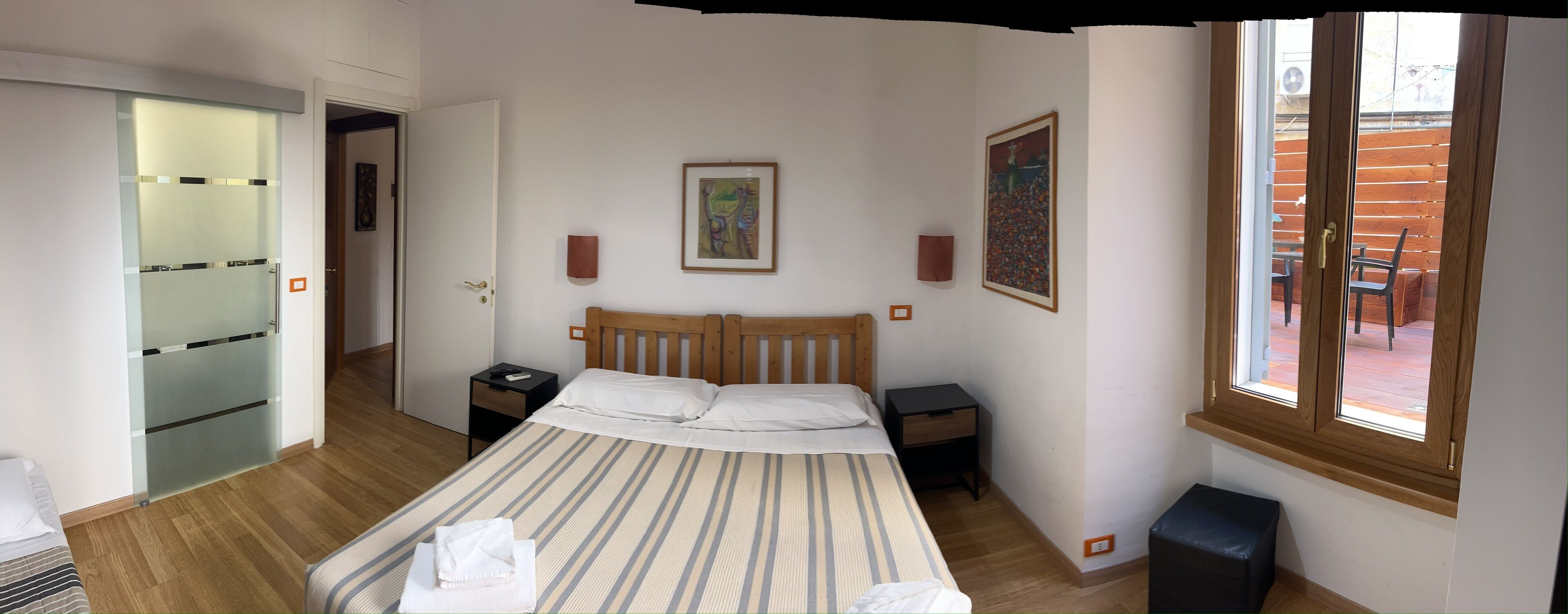 A bedroom with a bed, two bedside tables, a wardrobe, and a window.