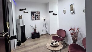 A modern living room with a wooden floor, a round coffee table, two red chairs, a bookshelf, and a 'Welcome Home' sign. - Maison Vaticana (Rome)