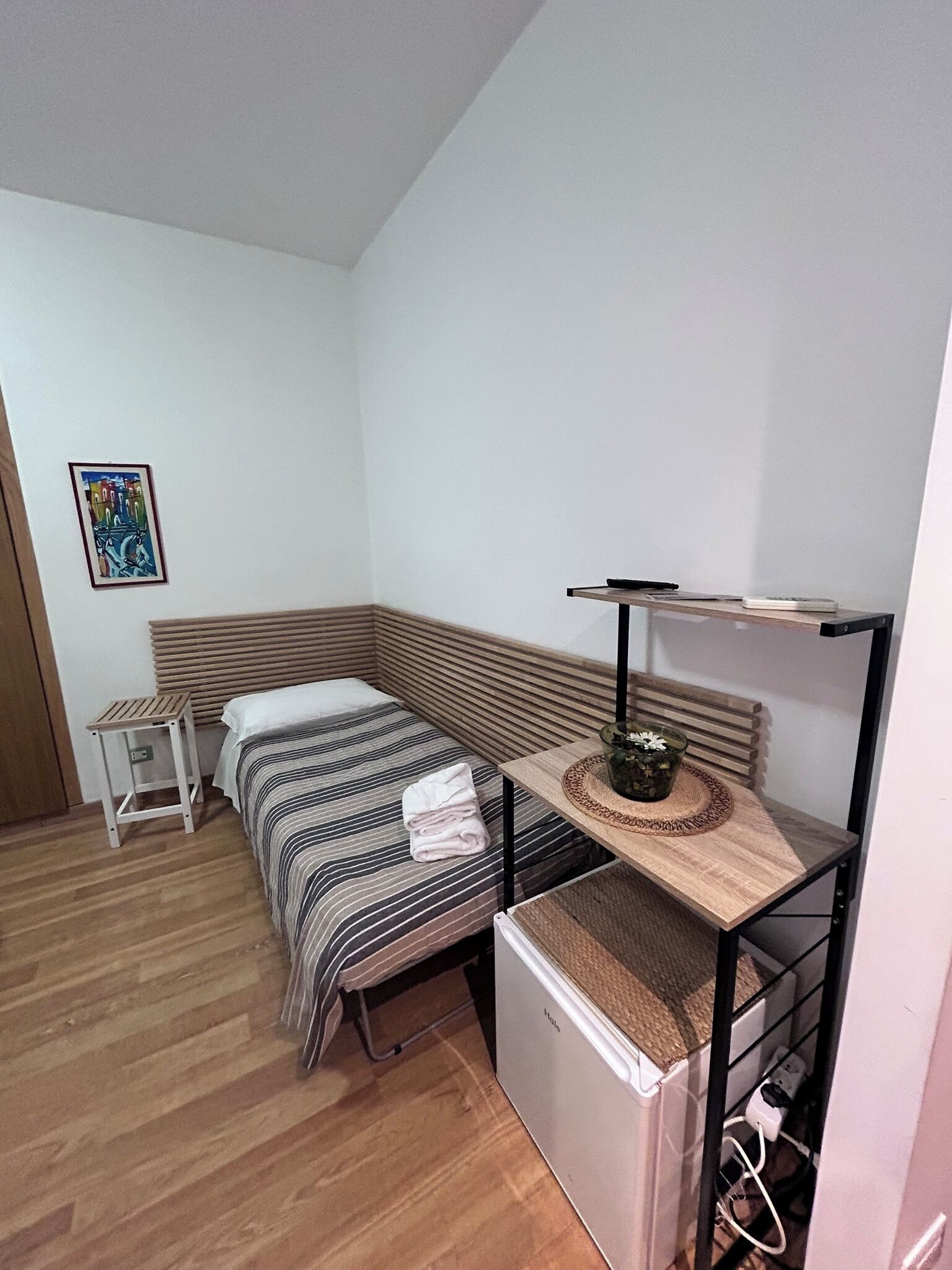 A small, compact room with a bed, a small table, and a desk with a chair.
