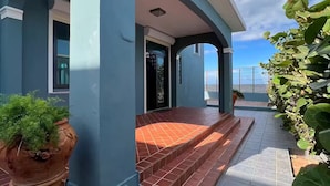 Ein Gebäude mit blauer Fassade, einer gefliesten Eingangshalle und einem Blumentopf.