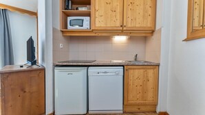A compact kitchen with wooden cabinets, a microwave, a dishwasher, and a small countertop. - 40m from ski slopes, 1st floor, fitness, swimming pool, sauna, balcony, tv, ski locker, 40m² (Les Orres)