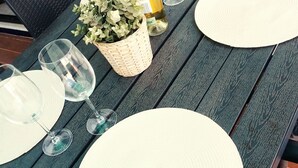 A dining table set with white placemats, wine glasses, and a bottle of white wine. - LUNA HOUSE 😎 (Santiago de la Ribera)
