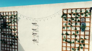 A white wall with wooden lattice windows and hanging decorations. - LUNA HOUSE 😎 (Santiago de la Ribera)