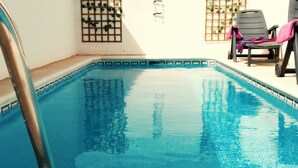 A clear blue pool with a metal ladder, surrounded by lounge chairs and greenery. - LUNA HOUSE 😎 (Santiago de la Ribera)