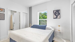 A bedroom with a bed, a window, and artwork on the walls. - Modern 3BR Near Beaches–Fast WiFi & Spacious Design (Fort Lauderdale)