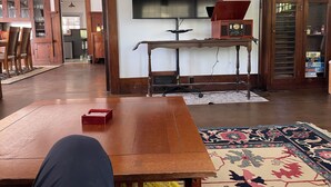 Een ruime woonkamer met een houten salontafel, een aan de muur bevestigde televisie en een vintage radio.