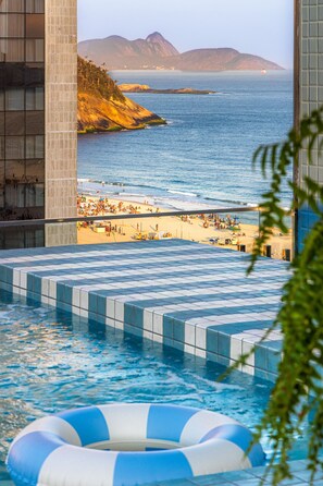 Una piscina infinita con vistas a una playa y montañas.