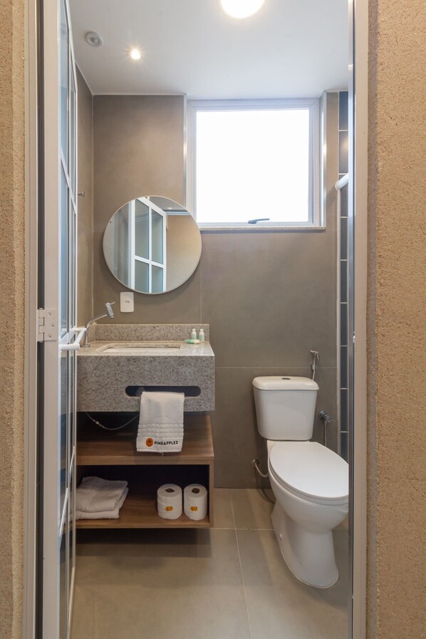 Un baño pequeño con lavamanos, espejo, inodoro y ventana que proporciona luz natural.