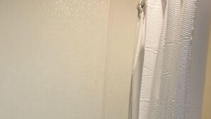 A bathroom with a toilet, a stack of toilet paper, and a bathtub with a shower curtain.
