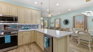 A kitchen with light blue walls, wooden cabinets, a stainless steel oven, and a large island with a sink.