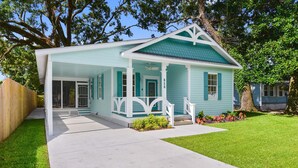 A light blue house with a porch, white trim, and a green roof.