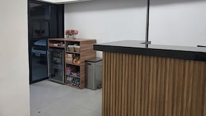 Cocina moderna con encimera de madera, refrigerador y puerta de vidrio que da a un estacionamiento.