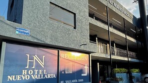 Un edificio de hotel con diseño moderno, una zona de recepción y un cartel que indica el nombre y la ubicación del hotel.