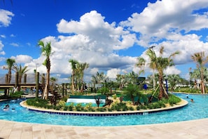 Une piscine bordée de palmiers, un espace abrité et un ciel d’un bleu limpide.
