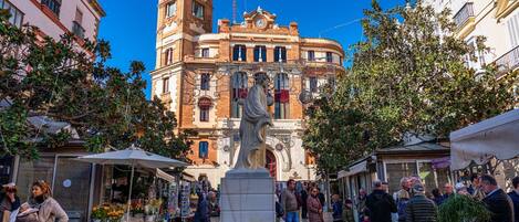 Una plaza pública con una fuente, rodeada de edificios y gente.