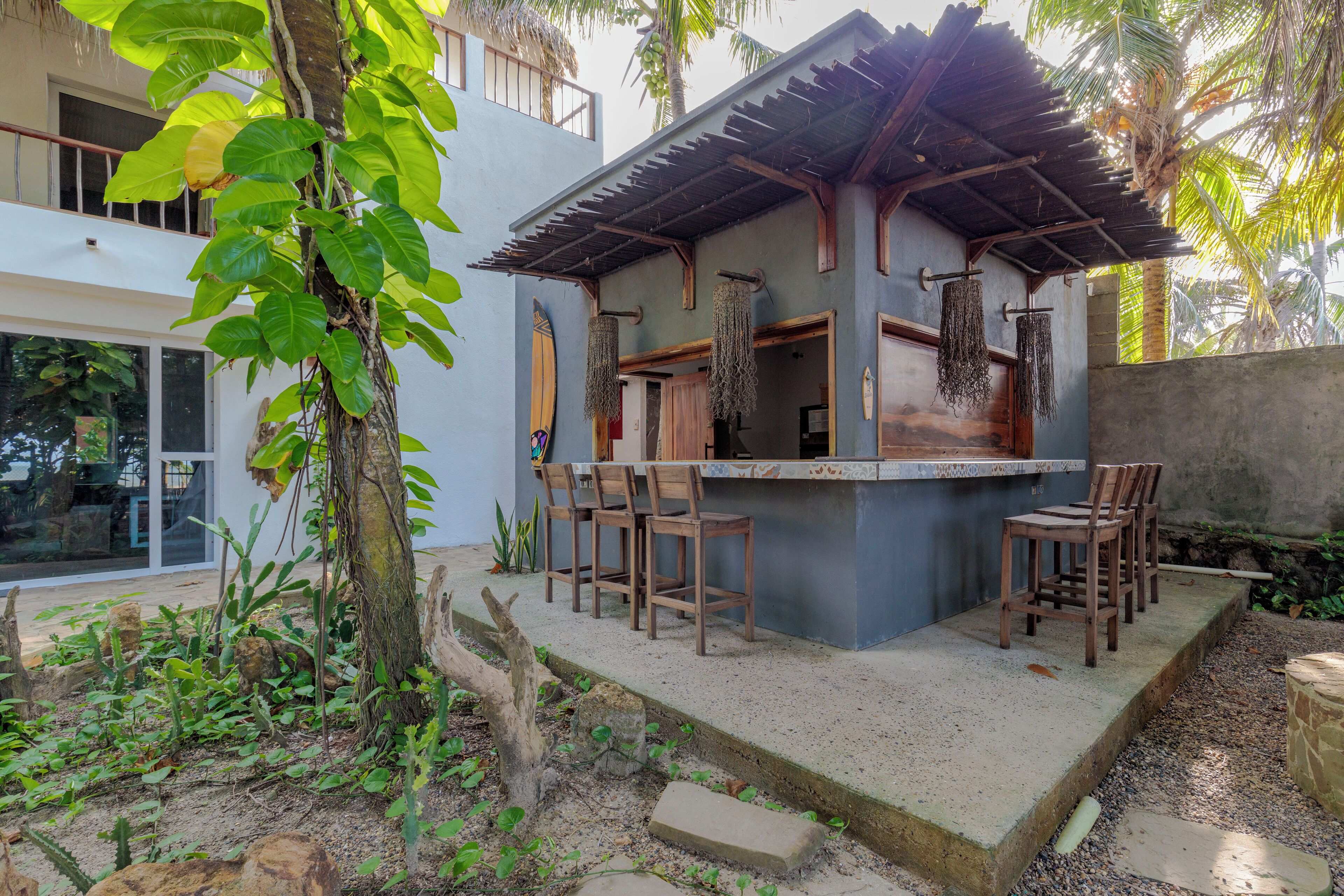 Un petit espace bar extérieur avec un comptoir en béton et des chaises en bois.