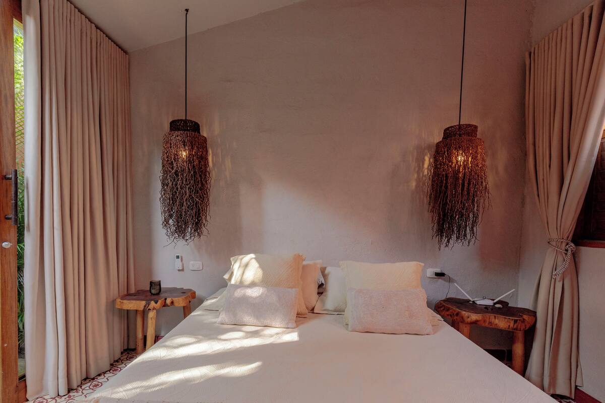 Ein Schlafzimmer mit einem Bett, zwei Hängelampen, einem Holztischchen und einem Nachttisch.