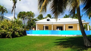 Une maison avec un toit blanc, des murs extérieurs bleus et une pelouse bien entretenue.