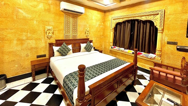 A hotel room with a checkered floor, a bed with a wooden headboard, an air conditioning unit, and a ceiling fan.