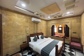 Habitación de hotel con cama, una silla, una mesita y un adorno en la pared.