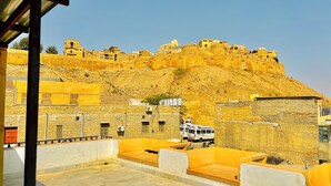 A view of a historic fort with yellow walls and a hilly backdrop.