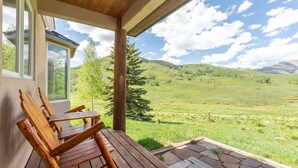 Eine Holzterrasse mit Stühlen mit Blick auf eine grüne Landschaft.