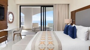 A hotel room with a bed, a desk, a chair, a television, and a view of the ocean.