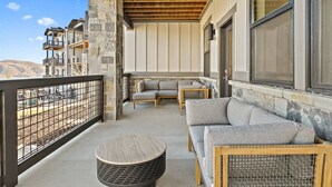 A balcony with a stone pillar, a round wooden table, and two sofas.