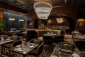 A restaurant with multiple dining tables, chairs, and a large chandelier.