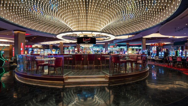 A casino with a central bar area, multiple gaming machines, and a distinctive ceiling light fixture. - Live Casino & Hotel Louisiana, Curio Collection by Hilton (Bossier City)