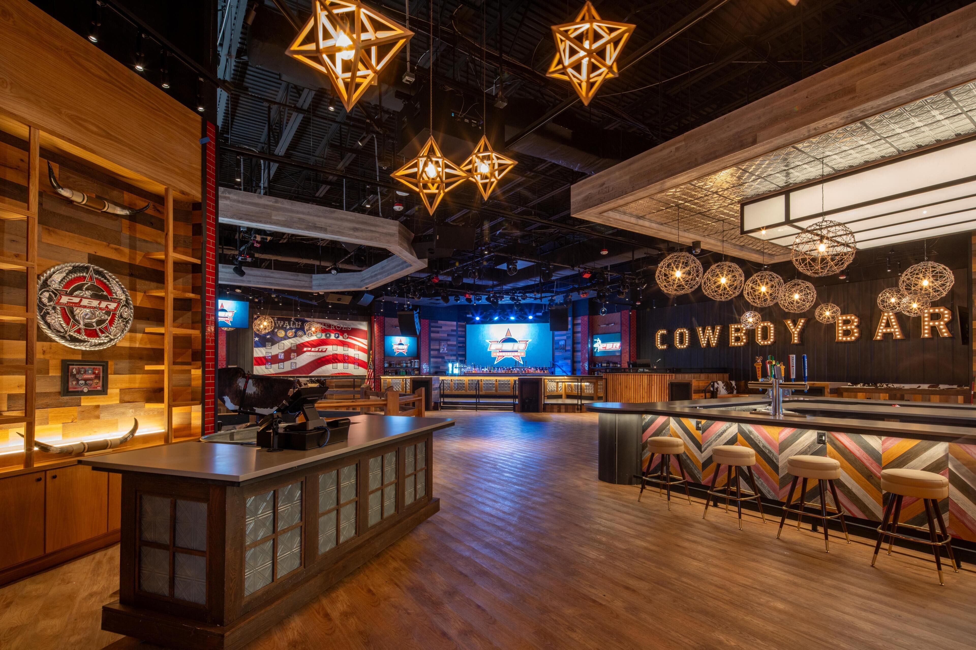 A bar area with a counter, stools, and a large screen displaying 'COWBOY BAR'.