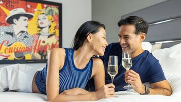 Um casal deitado em uma cama, com um quadro ao fundo.