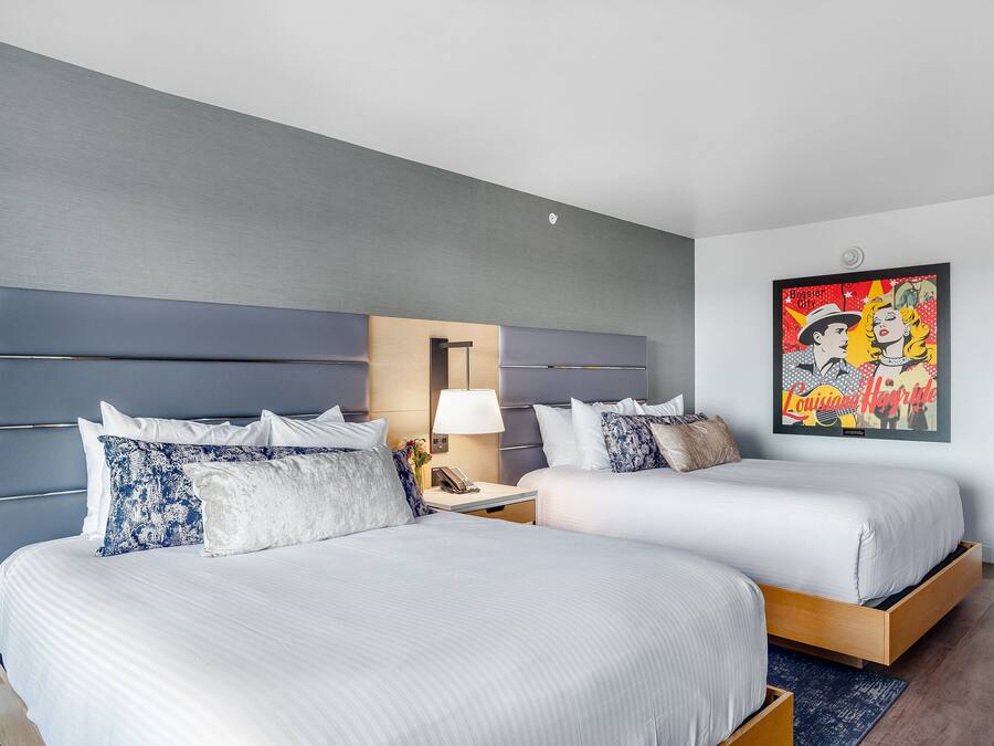 Ein Hotelzimmer mit zwei Betten, einem Nachttisch, einer Lampe und einem gerahmten Bild an der Wand.
